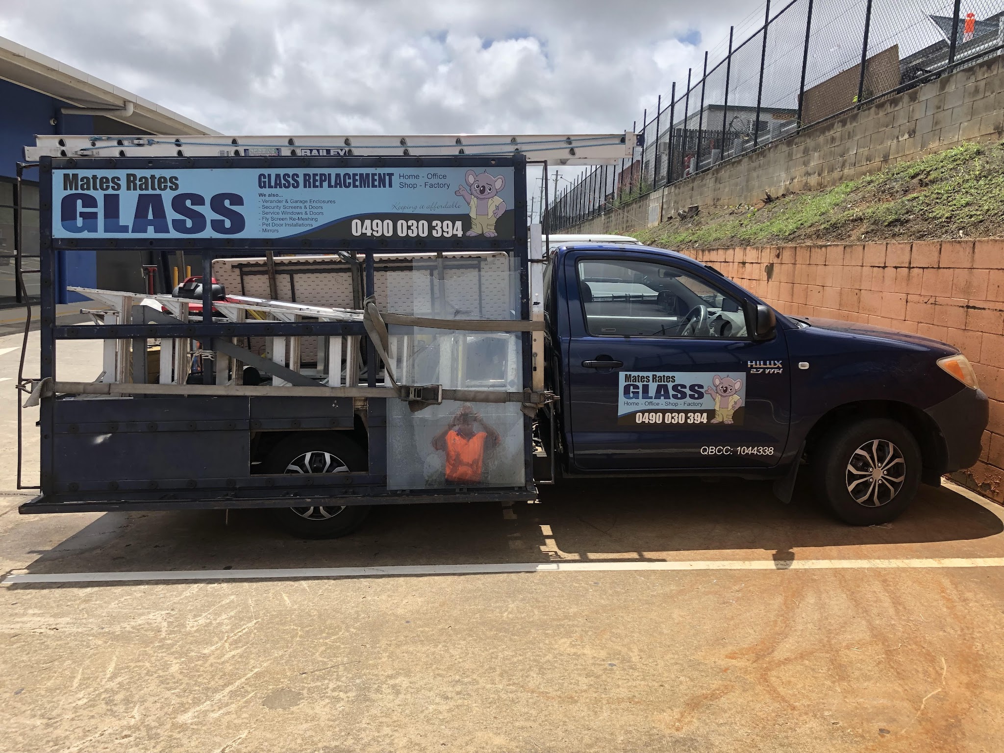 The Mates Rates Glass Toyota Hilux with glass rack, ladders and QBCC licence number on the door