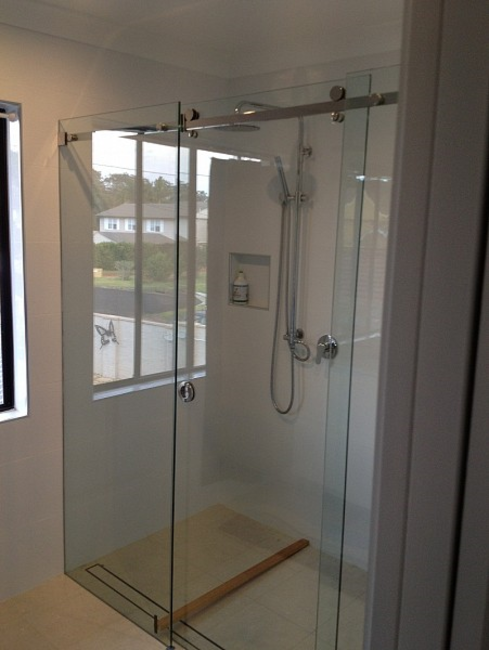 Sliding shower screen door above a tiled shower base