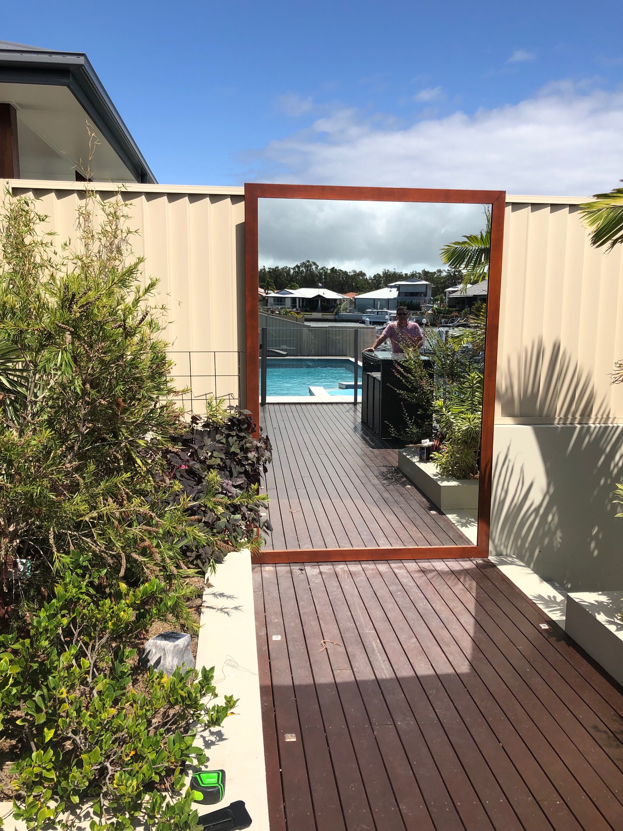 Large timber-framed outdoor mirror installed on a deck beside a pool