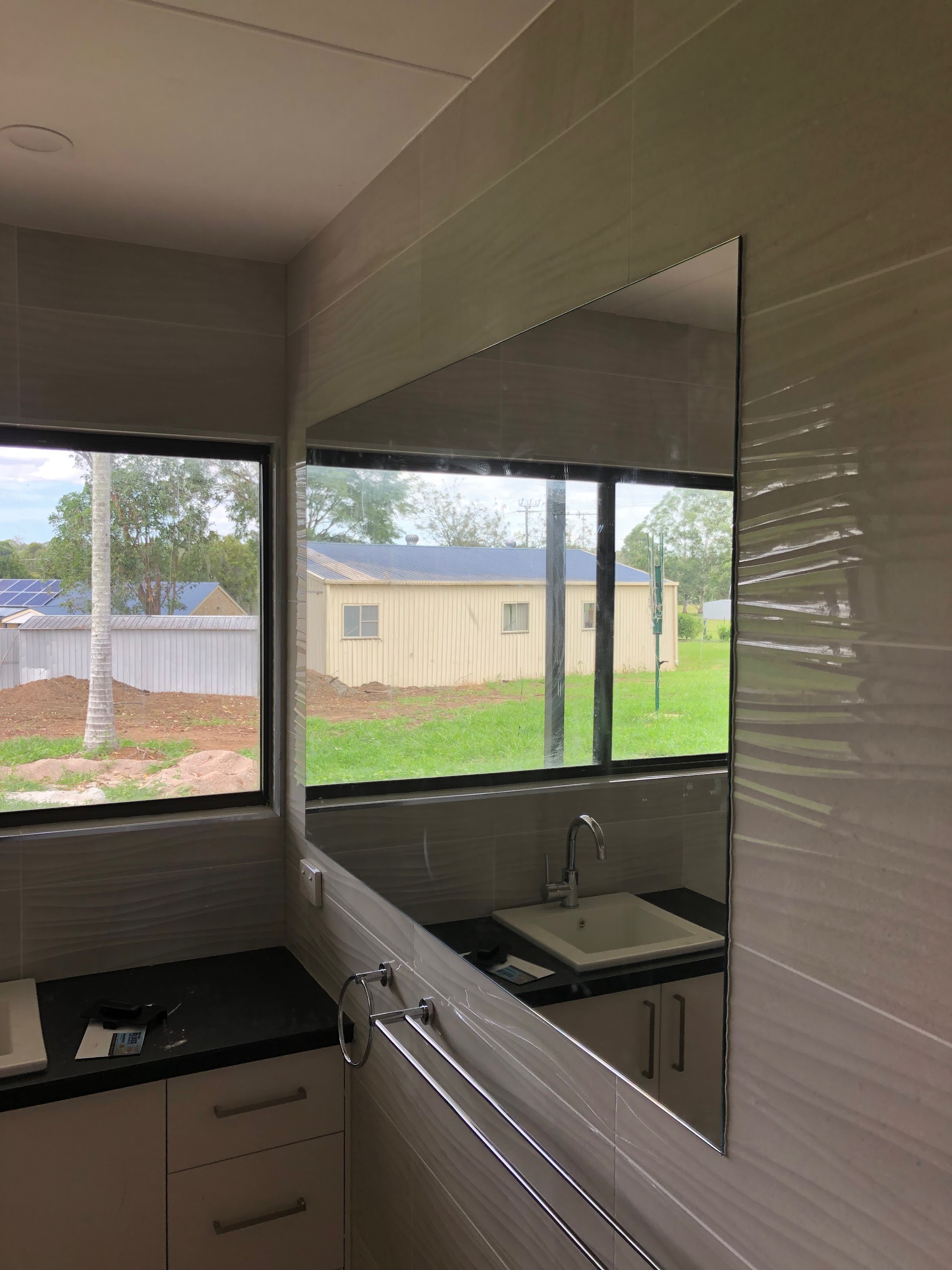 Wall mirror above a sink reflecting a rural property view